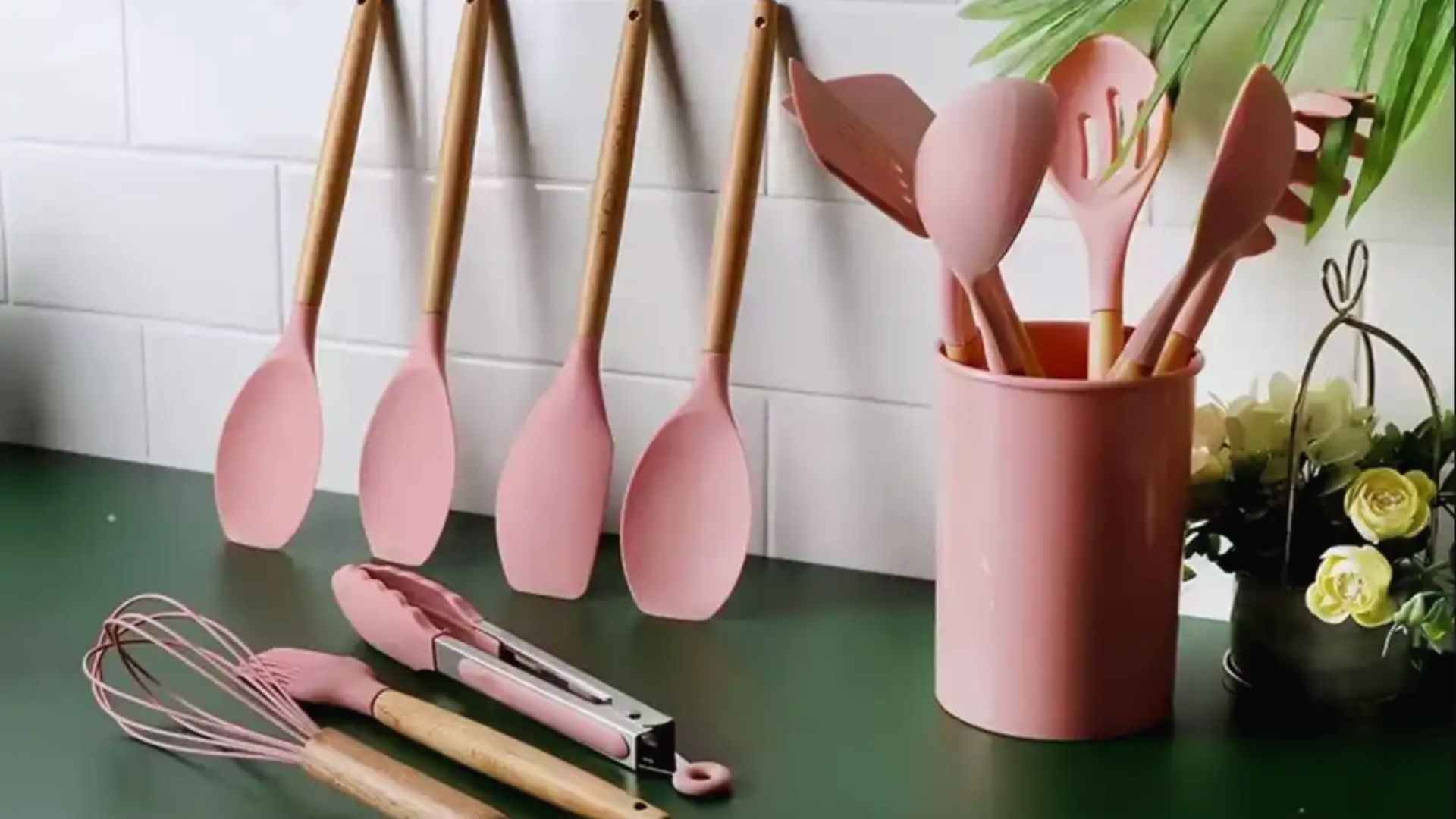 A collection of pink kitchen utensils and spoons arranged neatly on a countertop.