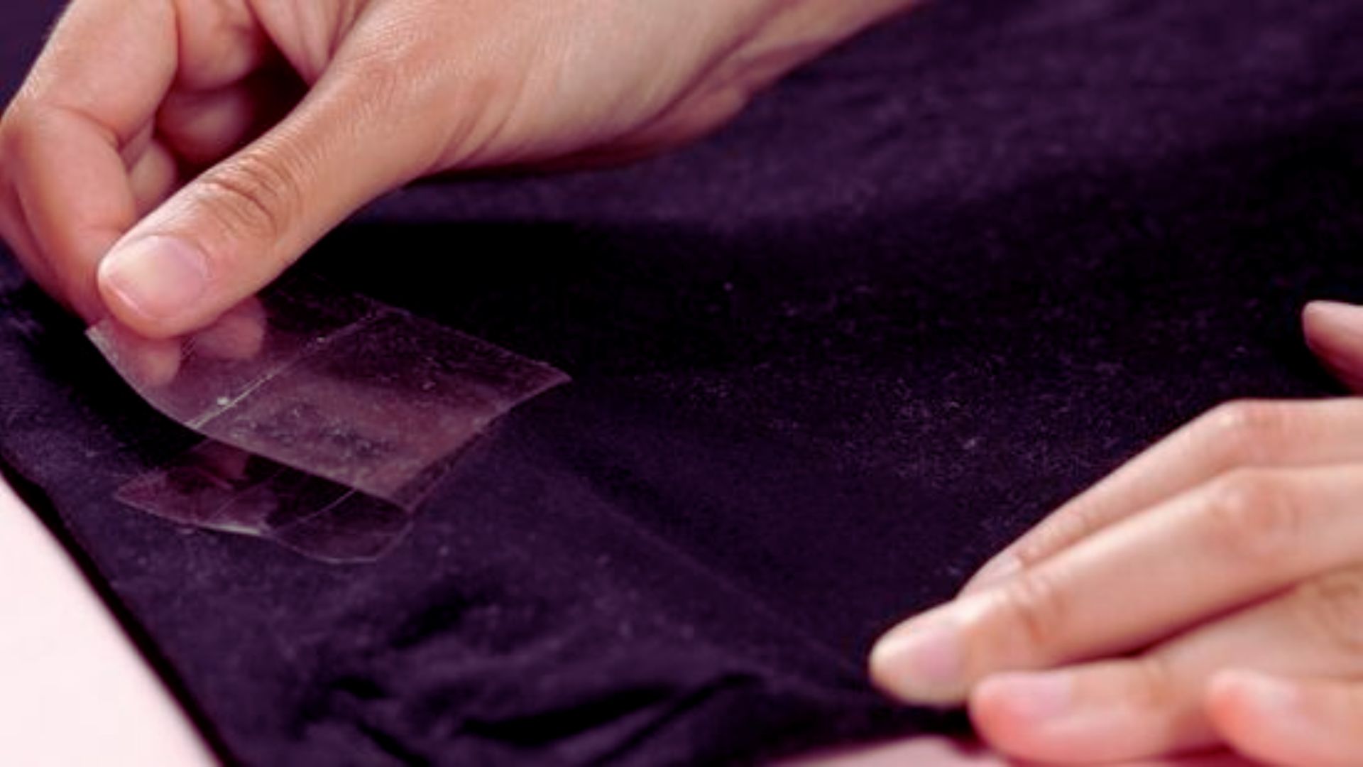 A person cuts fabric while holding a piece of tape, focusing on precise measurements for their project.