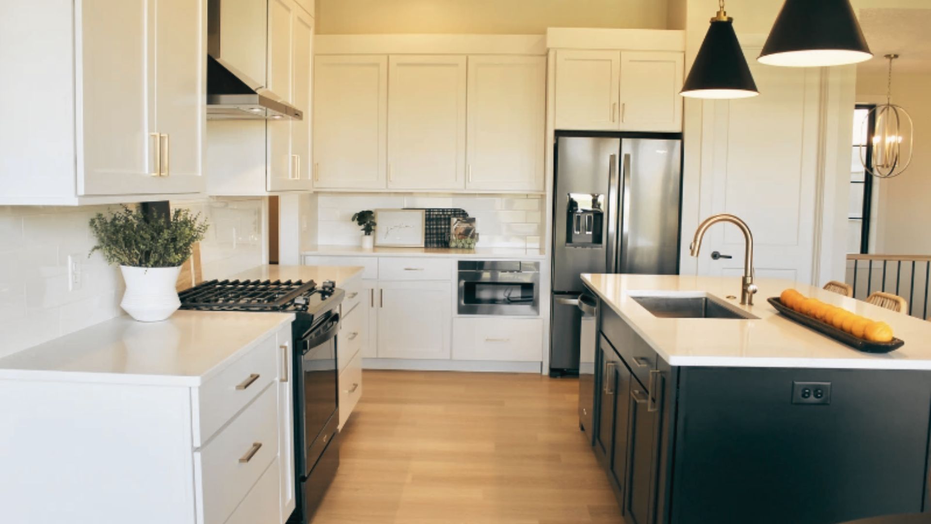 Modern Black and white kitchen with dark island contrast and stainless steel refrigerator.