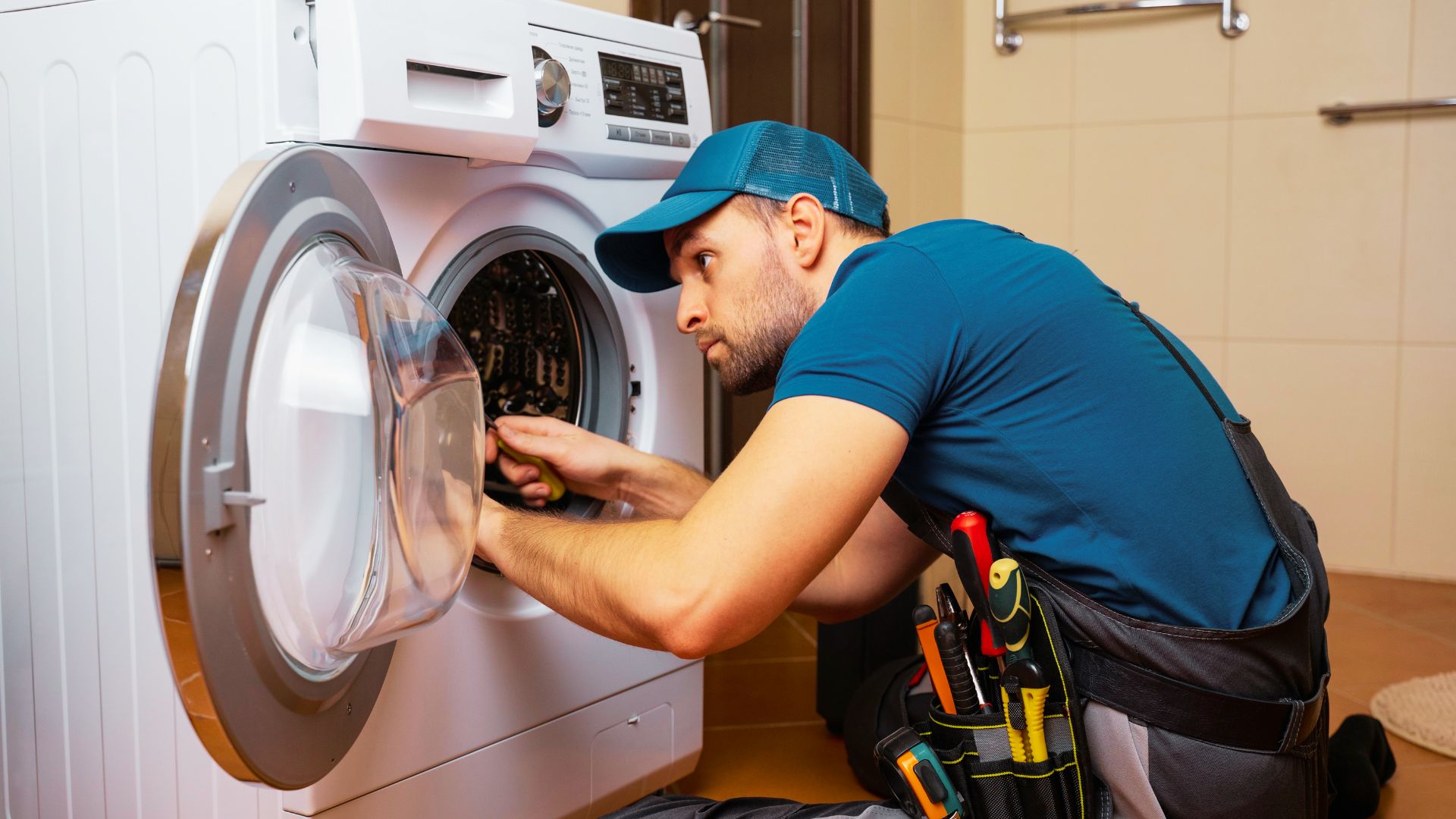 Technician troubleshooting front-load washer drum bearings to fix squeaking.