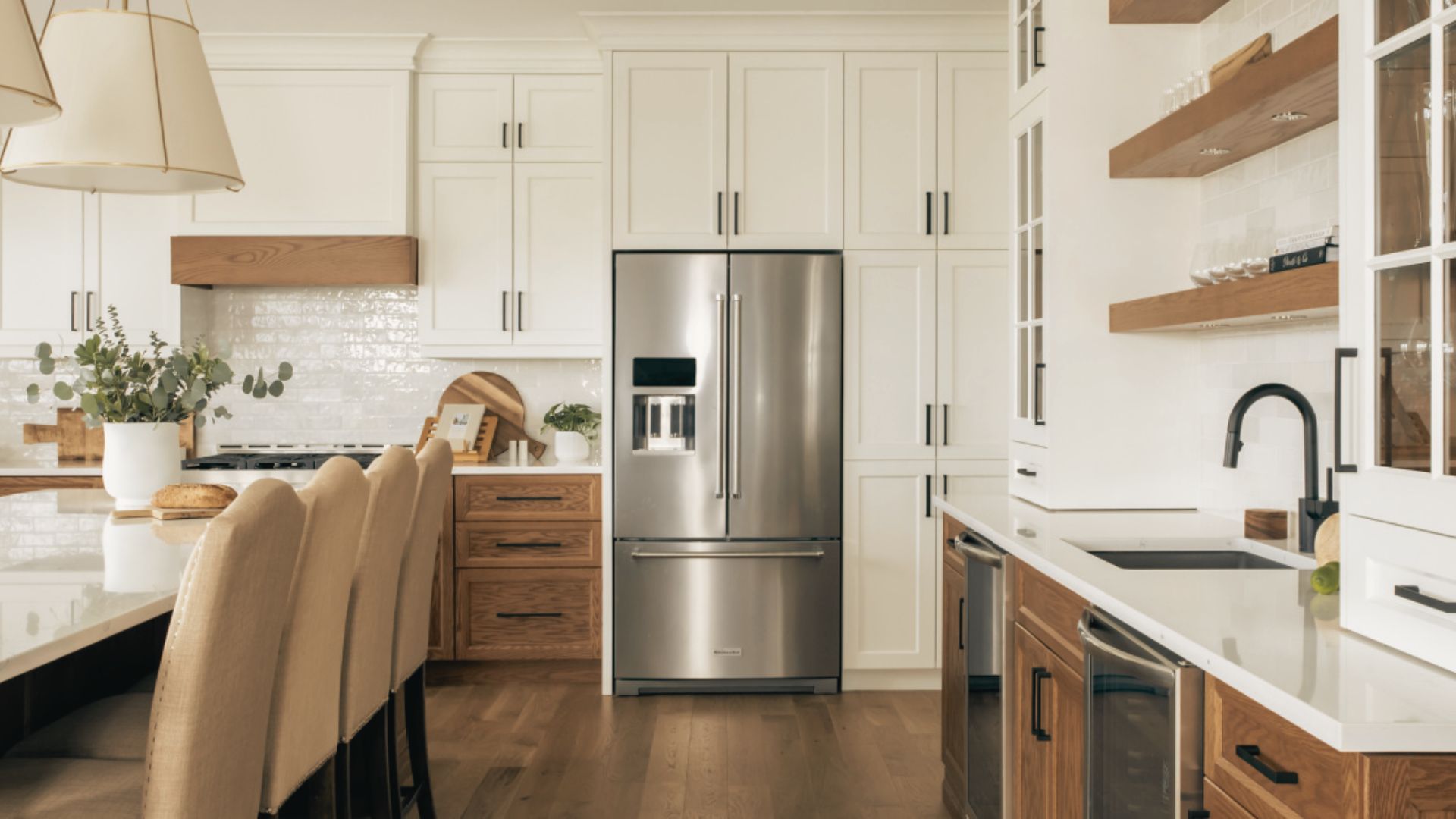 Farmhouse white L-shaped kitchen with stainless steel refrigerator and range hood.
