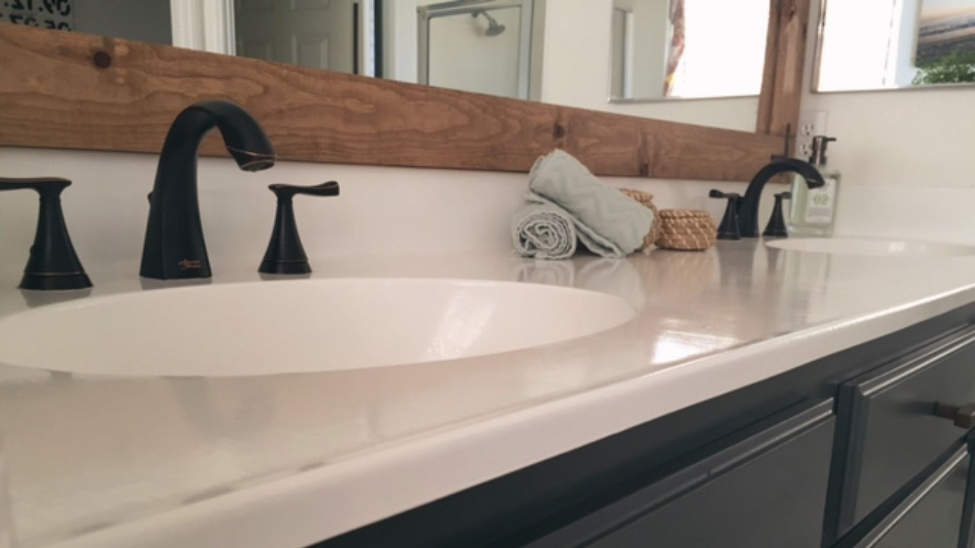 Refinished dual vanity with charcoal cabinets, white countertop, and matte black faucets installed