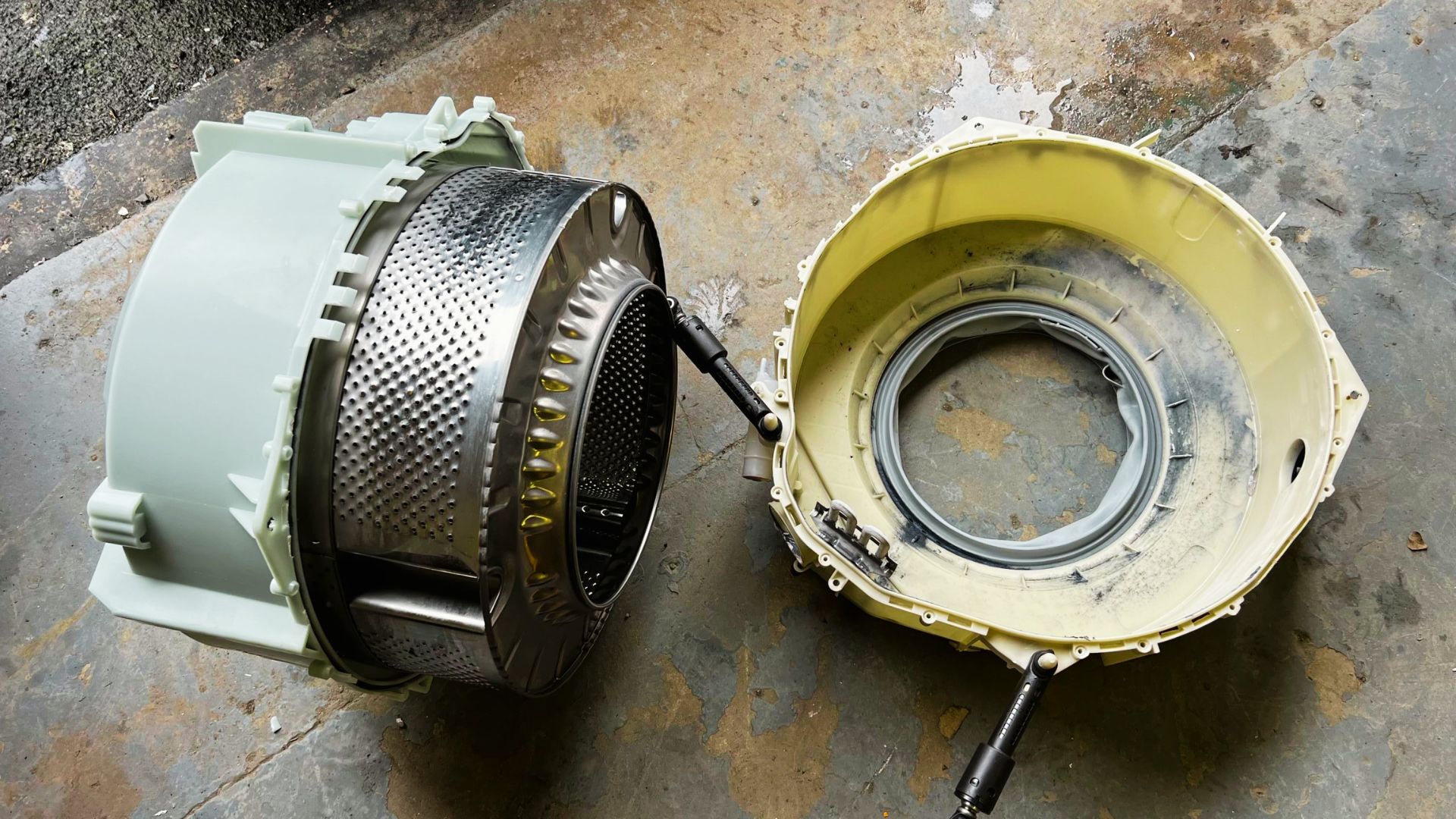 Disassembled washer drum with worn tub bearings causing grinding and squeaking.