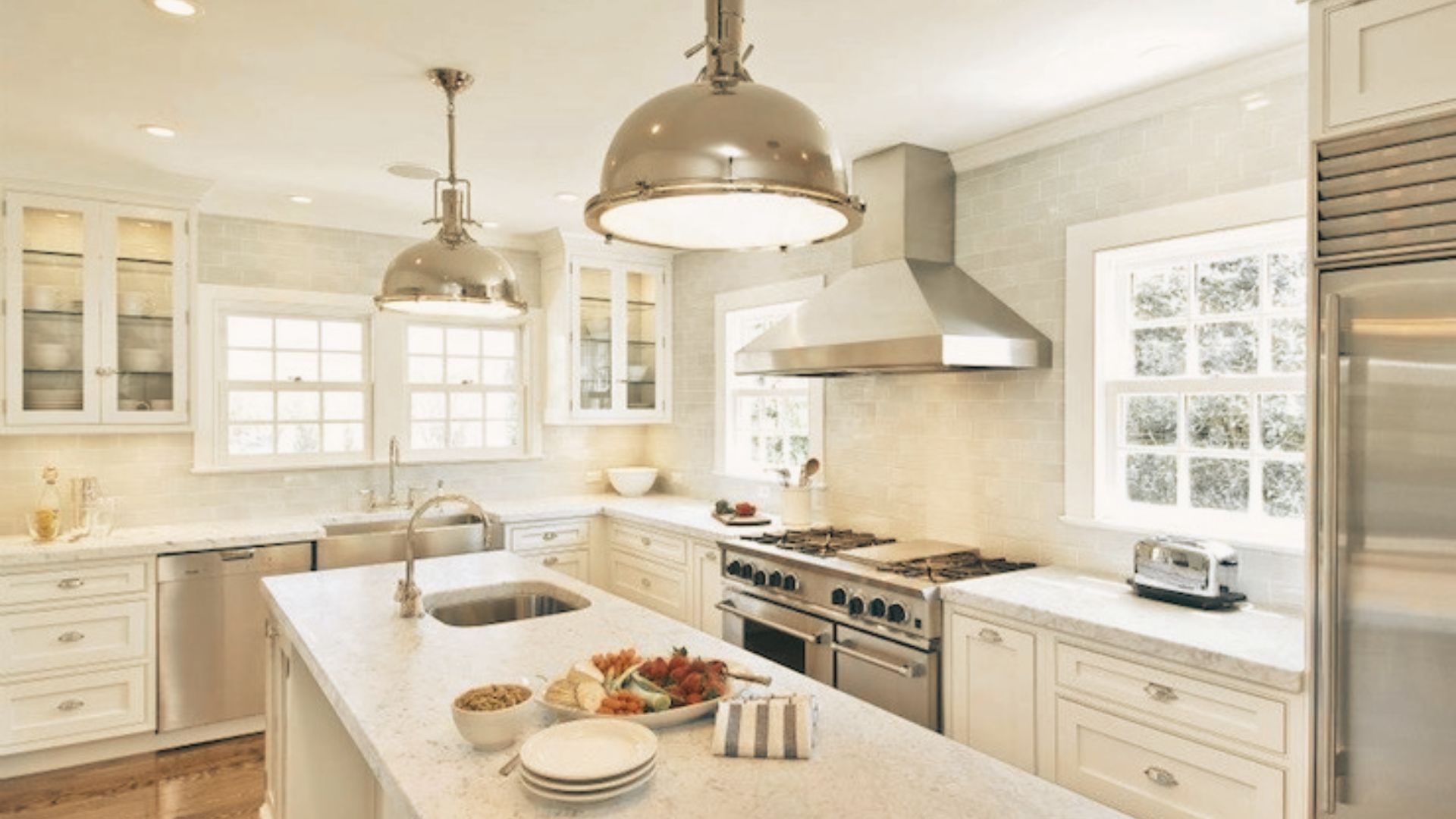 Bright white kitchen with stainless steel range hood and professional gas range.