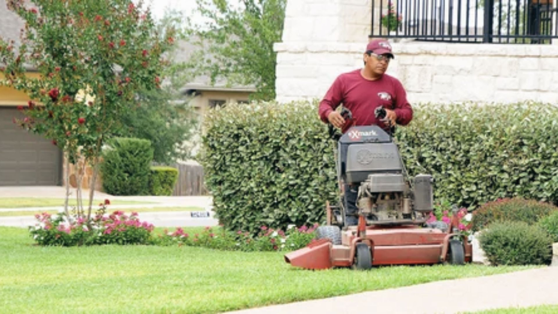 Worker on mower maintains front lawn and hedges to boost curb appeal and prevent pests