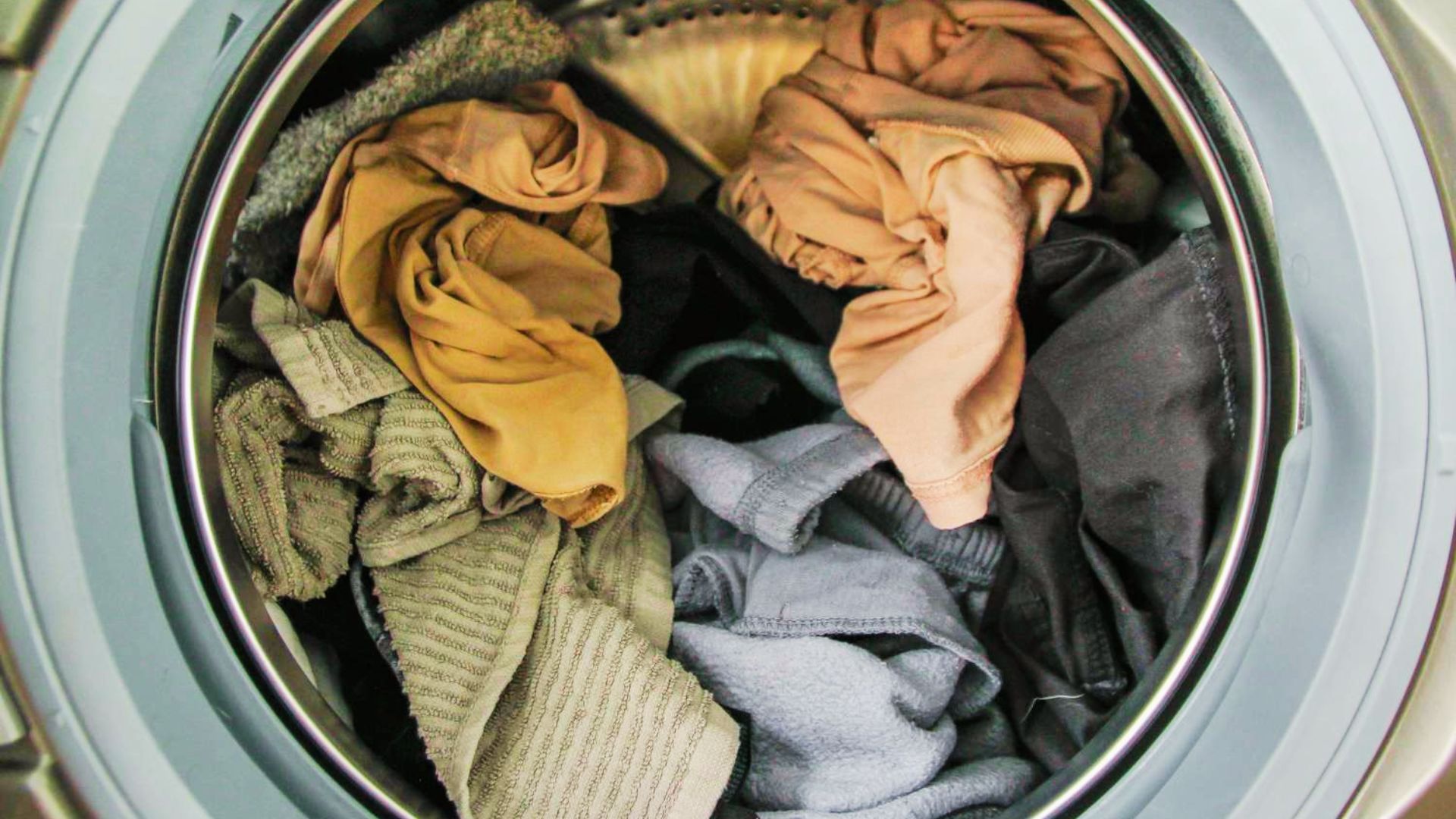Mixed damp clothes and towels fill a washing machine drum