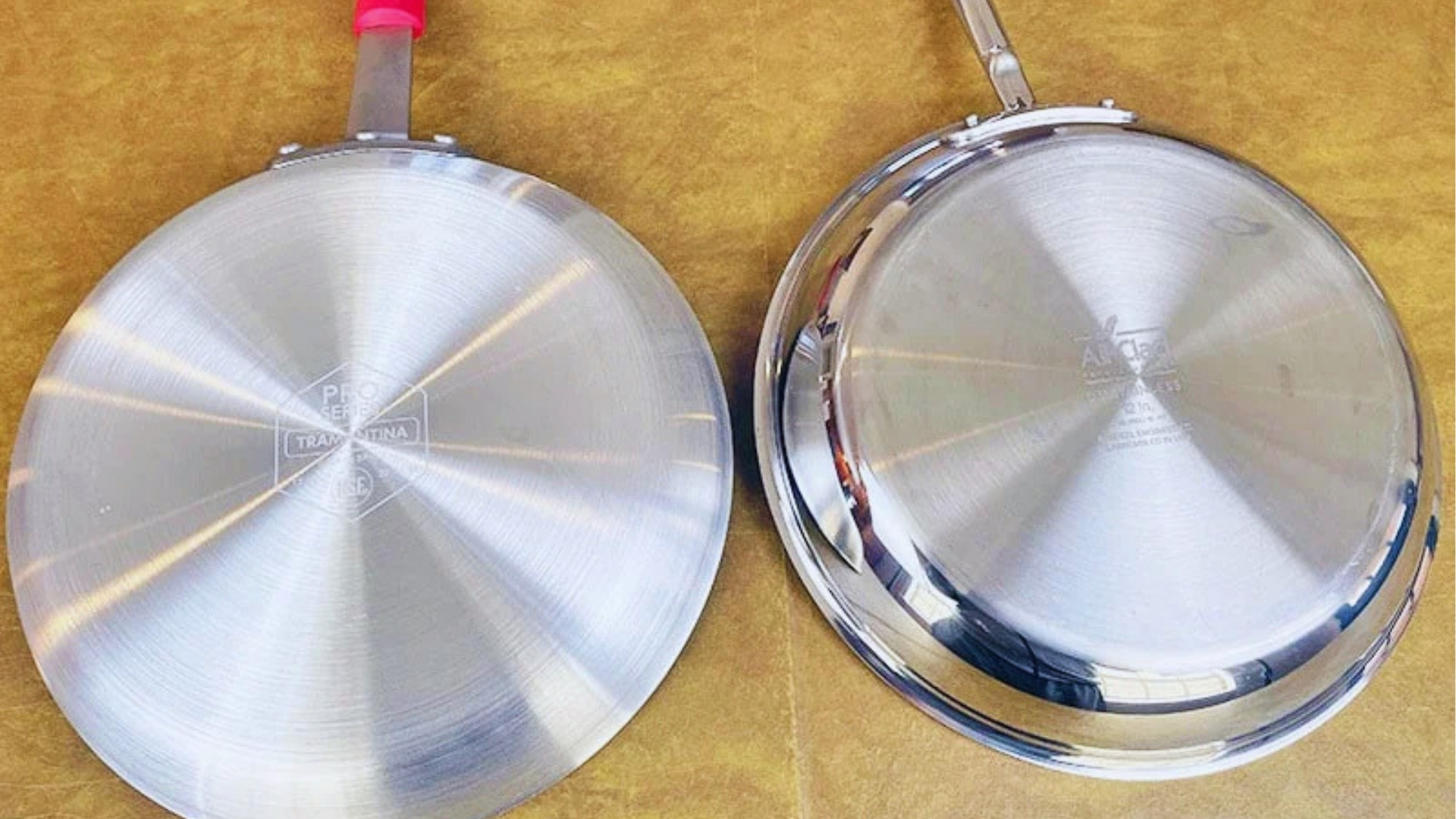 Bottom view of stainless steel and aluminum pan against brown surface.