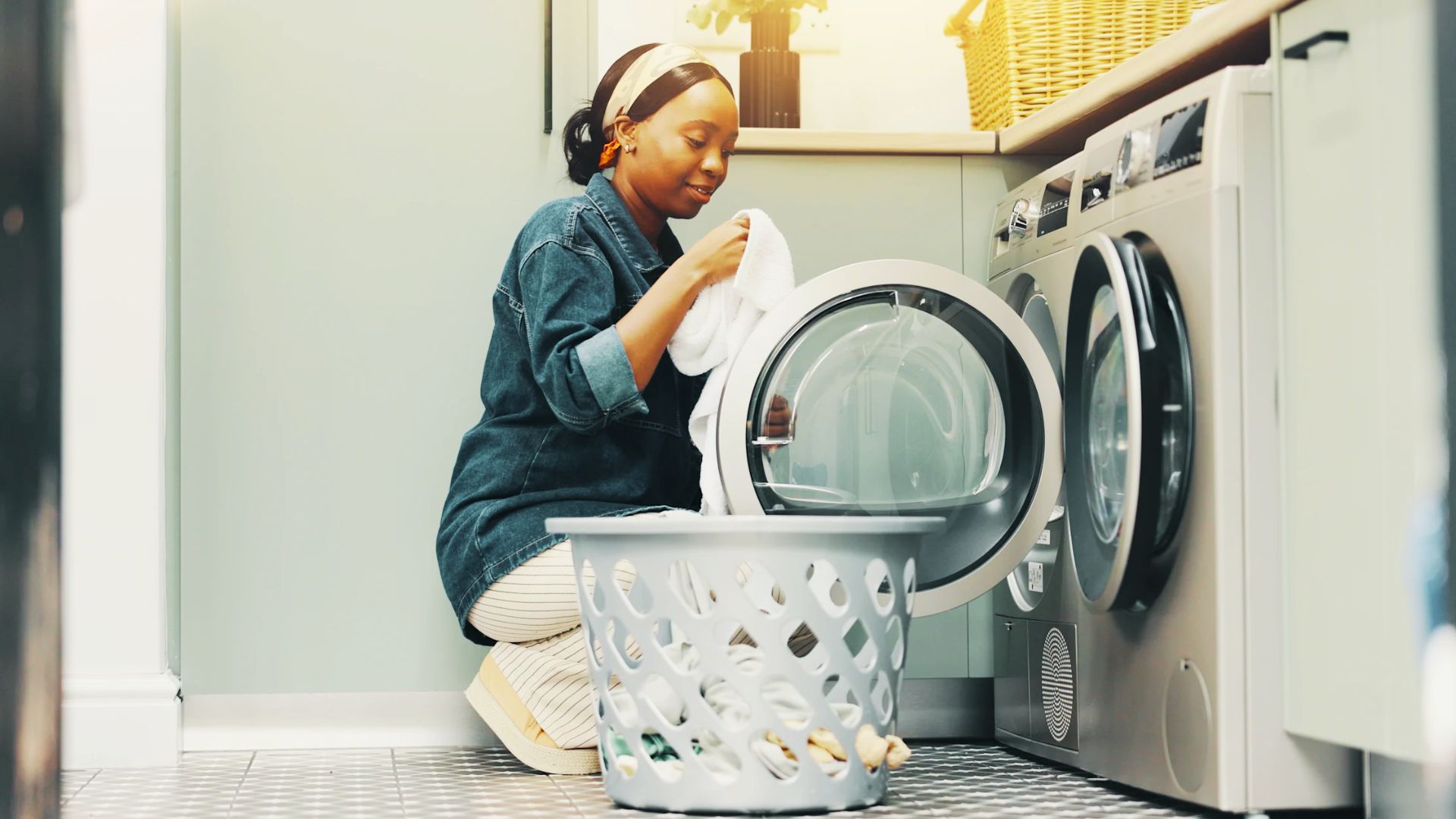 Woman loading white laundry into a front-load washer to kill bacteria with the high-heat sanitize setting