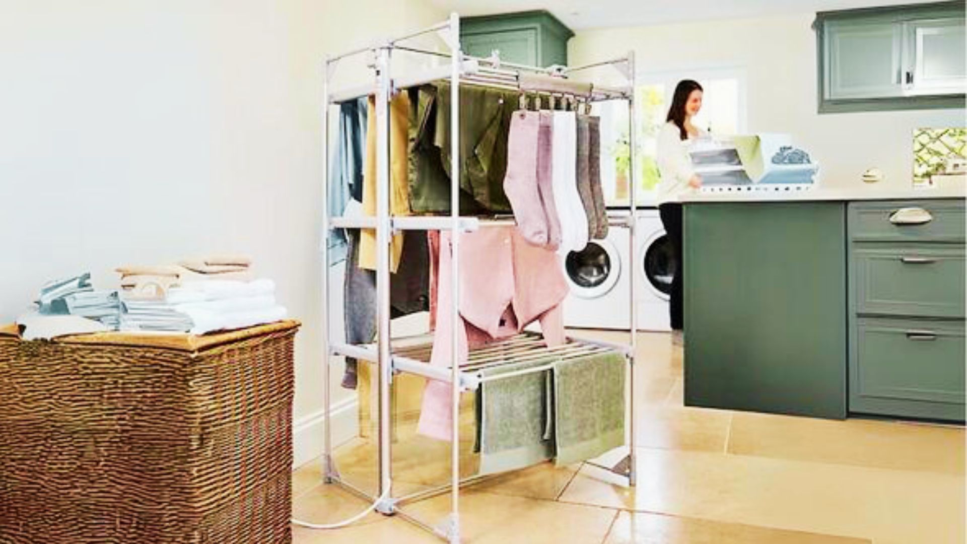 Colorful garments hang on a multi-tier indoor drying rack next to folded towels and a washing machine.
