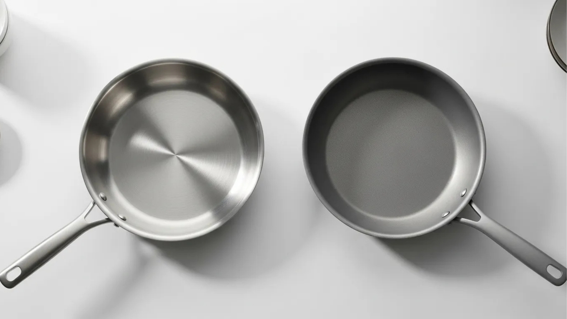 Top-down view of two frying pans side by side brushed stainless steel pan and aluminum pan.
