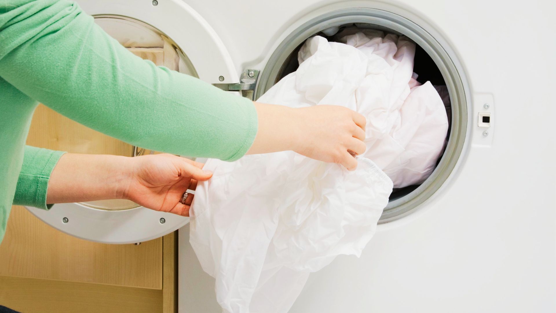 A person rewash clothes using hot water into a front-load washing machine.