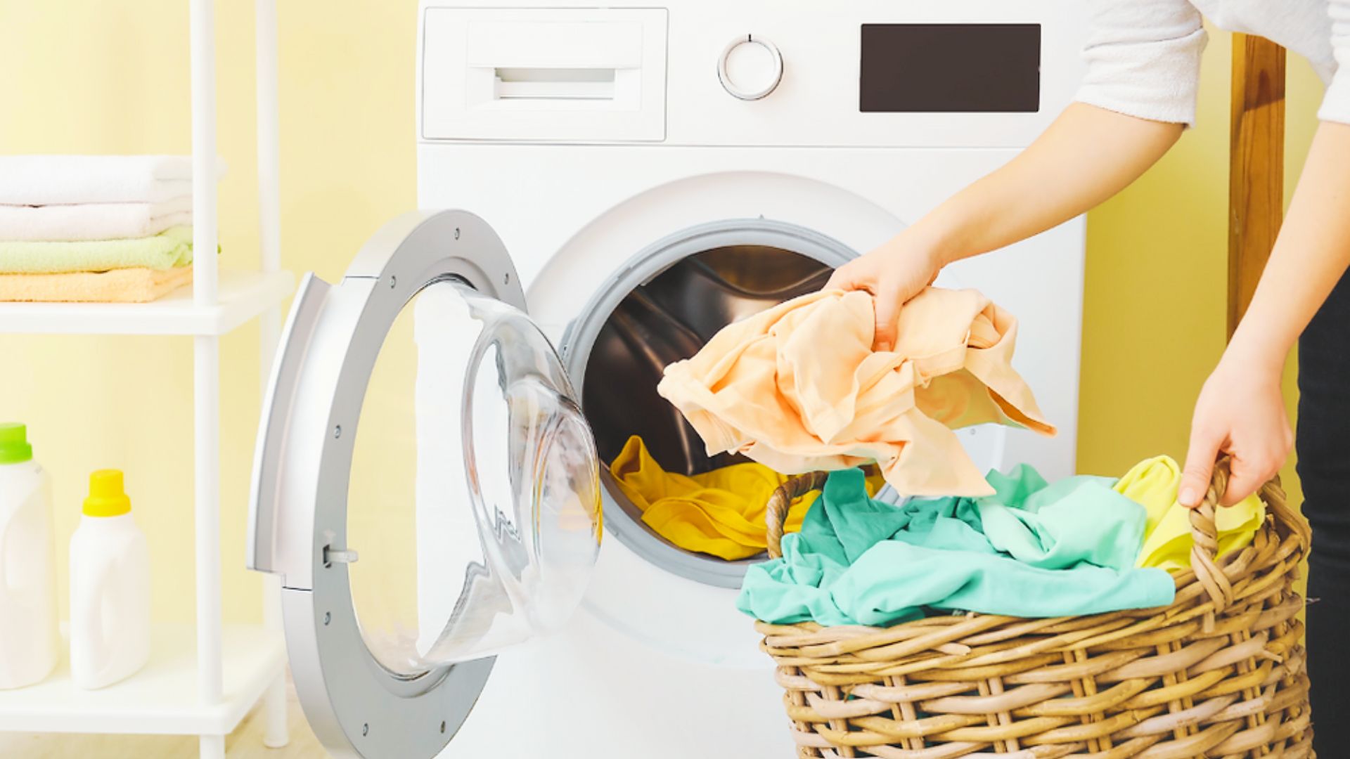 Person loading clothes from a basket into a washing machine before starting a quick wash.