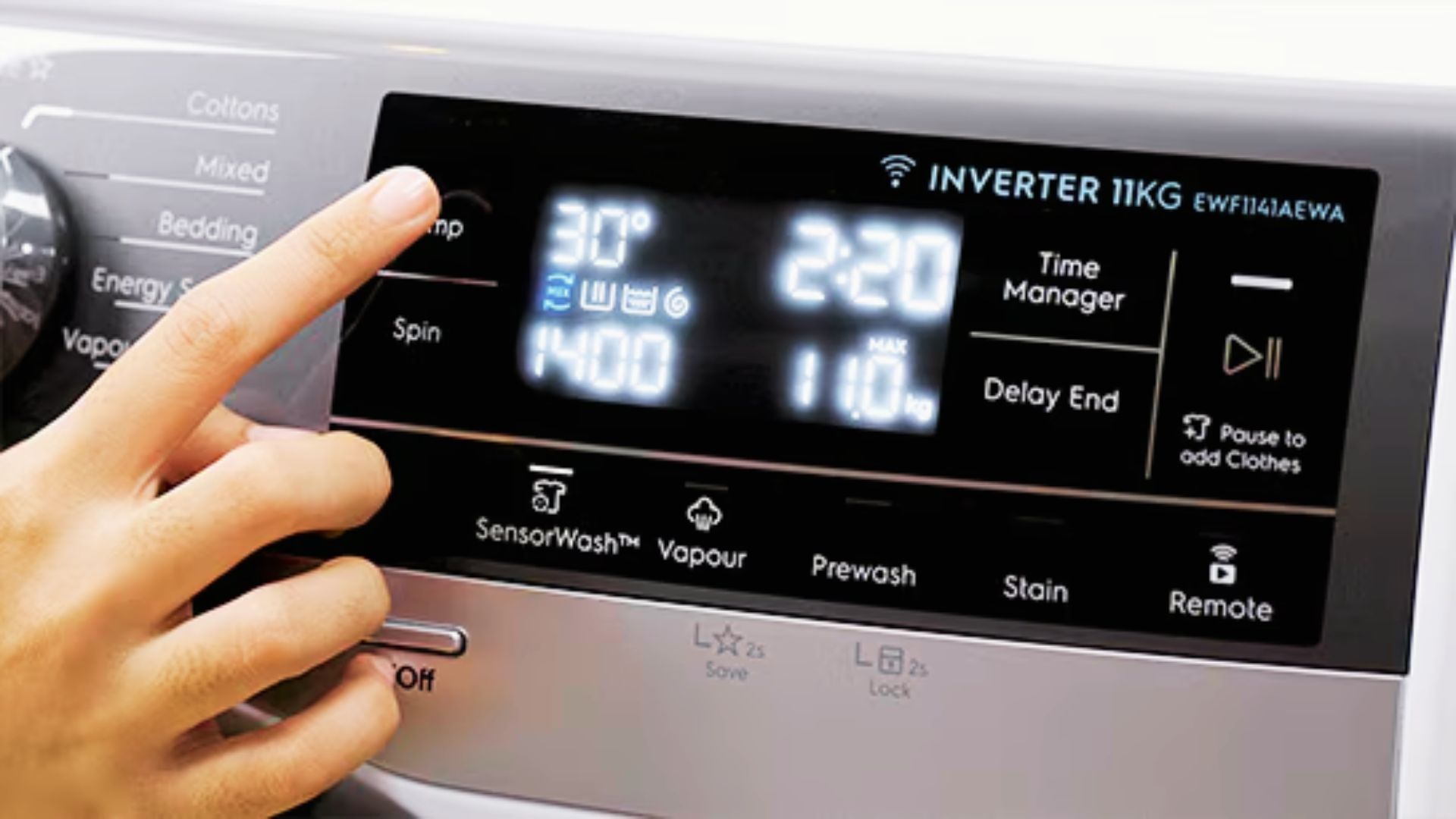 Finger pressing a button on a digital washer display while choosing a water temperature setting.