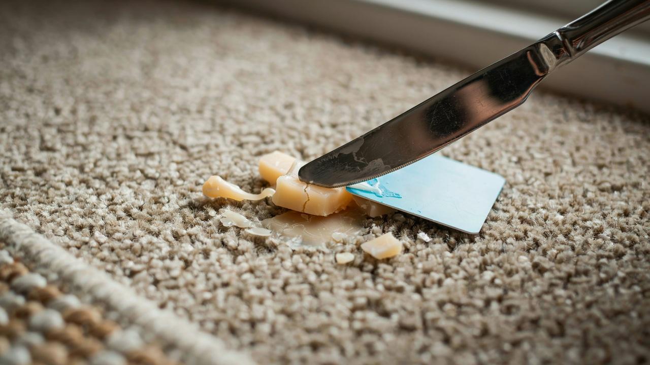 Scraping hardened candle wax from carpet safely.