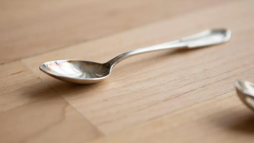 Close-up of tarnished silver showing dull and darkened areas compared to shiny polished sections.