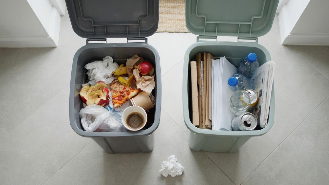 Two household bins showing separated trash and recyclable materials in a clean, organized storage area.